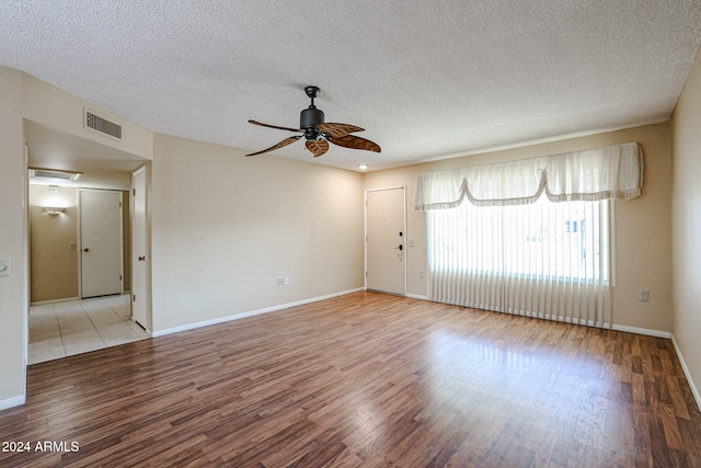 spare room with ceiling fan, light wood-type flooring, and a textured ceiling