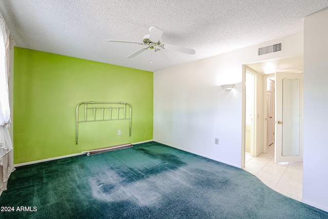 spare room with ceiling fan, light carpet, and a textured ceiling