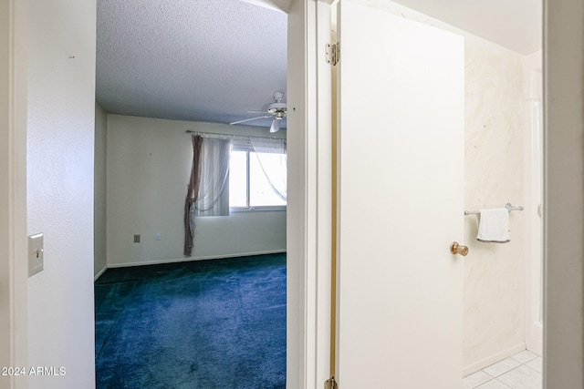 corridor featuring light colored carpet and a textured ceiling