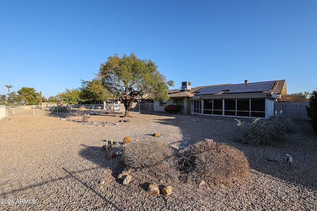 back of property featuring a sunroom and solar panels