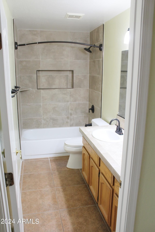 full bathroom featuring tile flooring, vanity, tiled shower / bath combo, and toilet