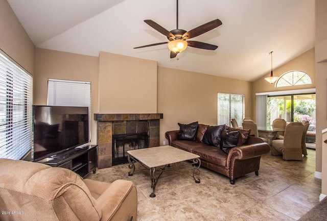 living room with a tile fireplace, ceiling fan, and vaulted ceiling