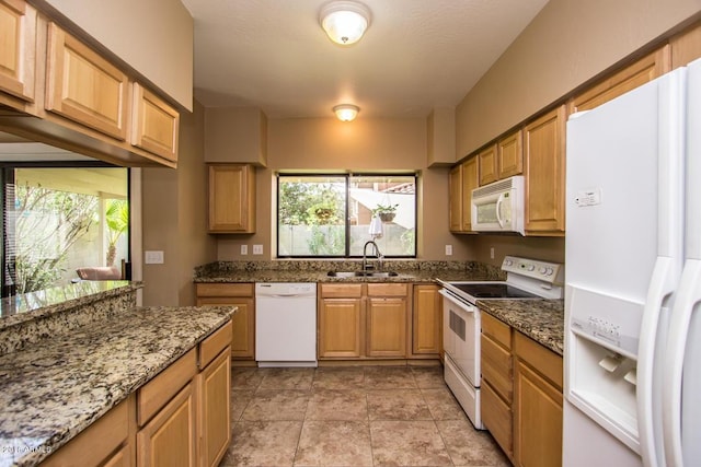 kitchen with white appliances, stone countertops, a healthy amount of sunlight, and sink