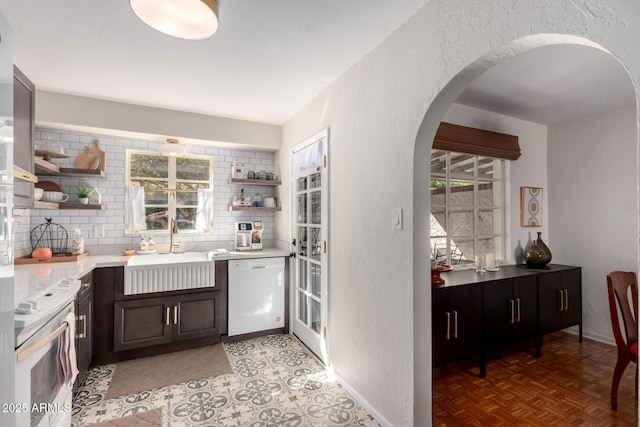 kitchen featuring white appliances, arched walkways, open shelves, and a sink