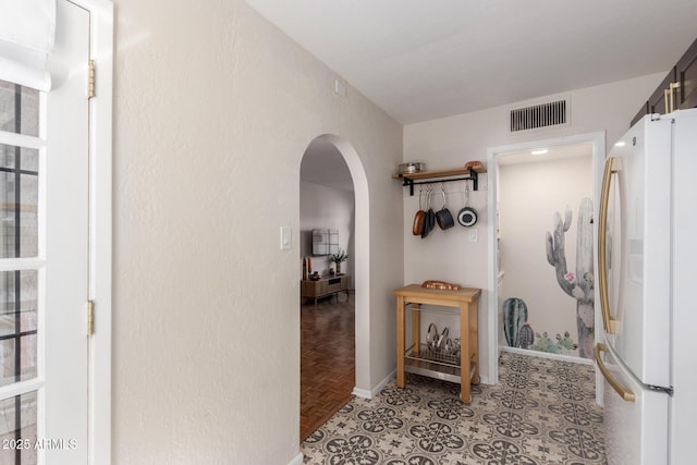 hallway featuring arched walkways, visible vents, and baseboards