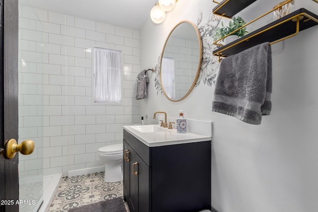 full bathroom featuring toilet, vanity, a tile shower, and tile patterned floors