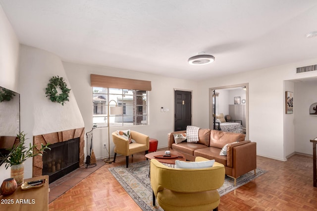 living area with baseboards, visible vents, and a tiled fireplace