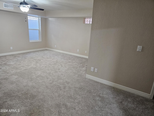 empty room featuring carpet flooring, ceiling fan, baseboards, and a textured wall