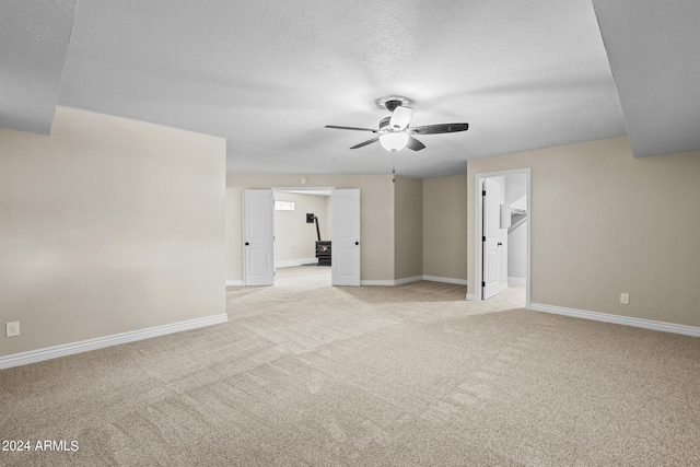 empty room featuring light carpet, a textured ceiling, and ceiling fan