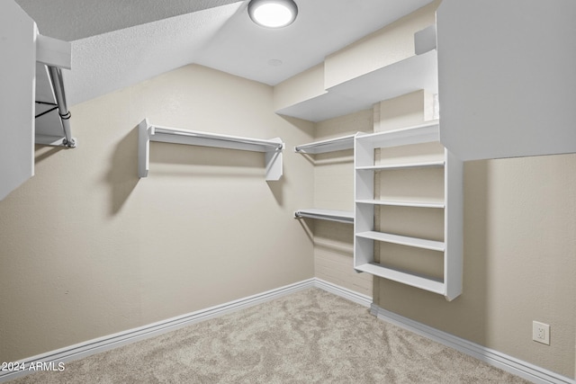 walk in closet featuring light carpet and lofted ceiling