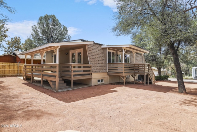 view of front of house with french doors, a deck, and fence