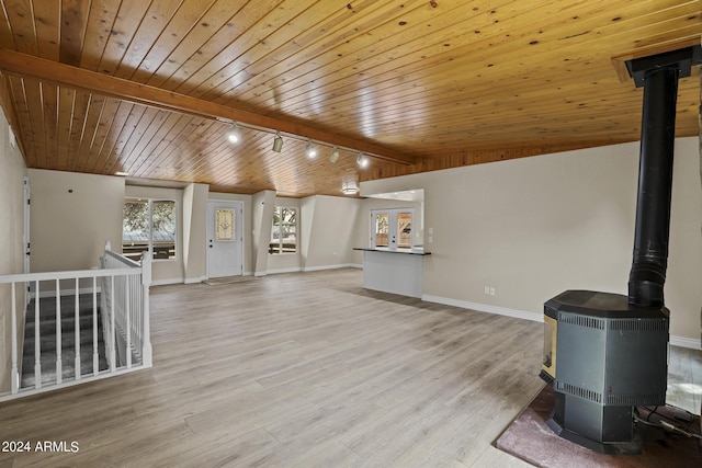 unfurnished living room featuring a wood stove, wooden ceiling, light hardwood / wood-style floors, lofted ceiling, and track lighting