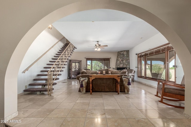 8043 E Laurel St, Mesa, AZ 85207 - living area with arched walkways, stairway, a ceiling fan, a fireplace, and light tile patterned floors