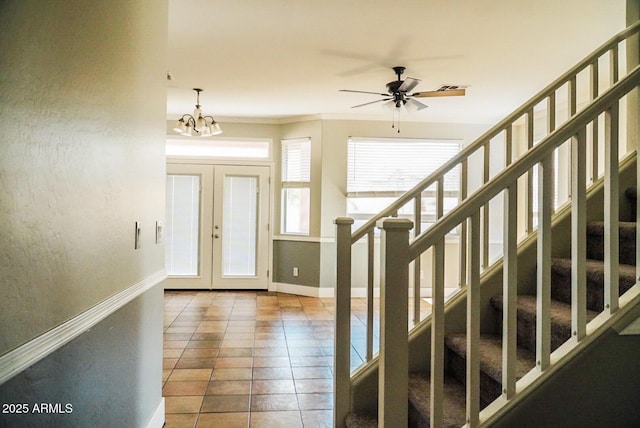 tiled foyer with ceiling fan with notable chandelier and french doors