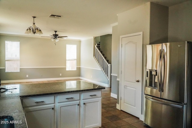 kitchen featuring white cabinetry, a wealth of natural light, stainless steel fridge, and dark stone countertops