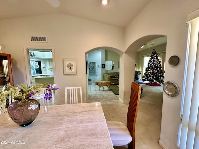 dining space with light carpet and vaulted ceiling