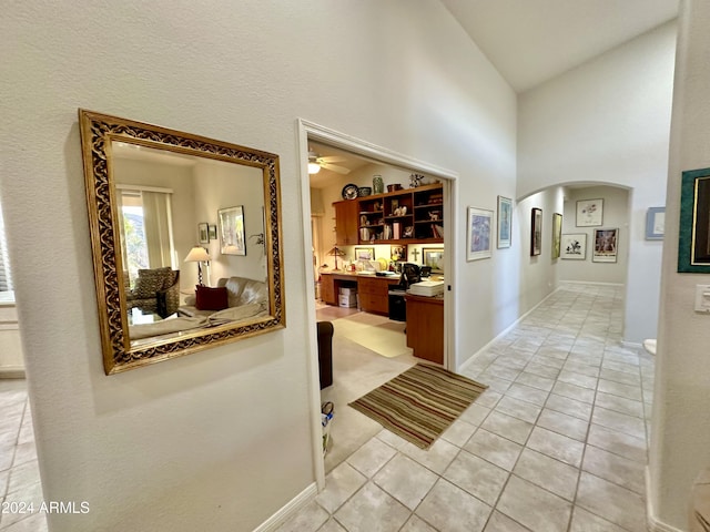 corridor featuring light tile patterned floors and high vaulted ceiling