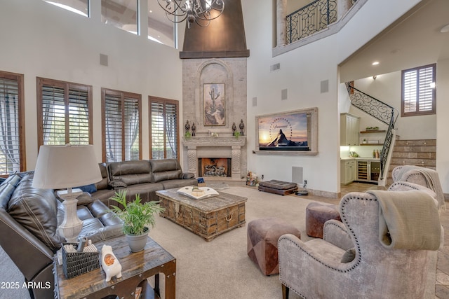 living room with an inviting chandelier, a large fireplace, a towering ceiling, and carpet floors