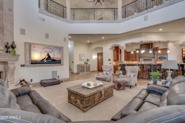 carpeted living room with a fireplace, a notable chandelier, and a high ceiling