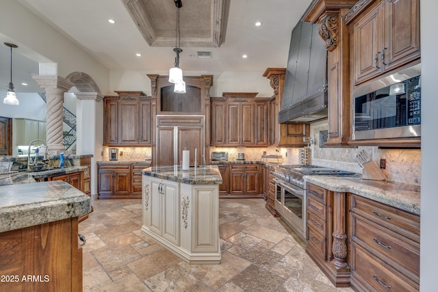 kitchen with a raised ceiling, backsplash, hanging light fixtures, and built in appliances