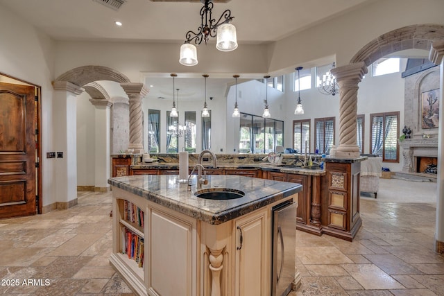 kitchen with decorative columns, hanging light fixtures, and a center island with sink