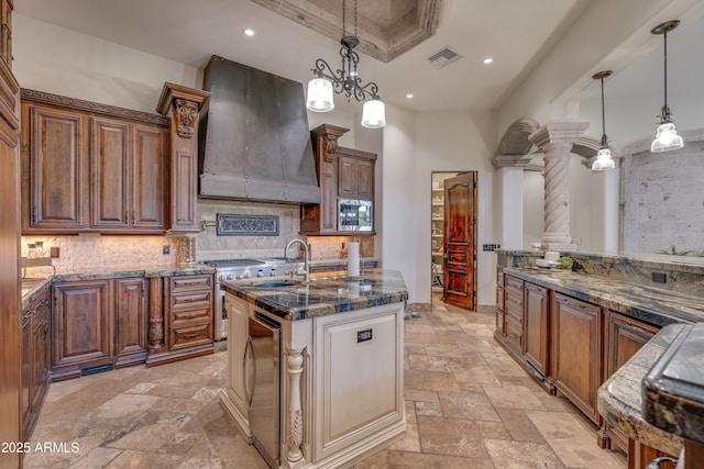 kitchen with tasteful backsplash, custom exhaust hood, sink, hanging light fixtures, and ornate columns