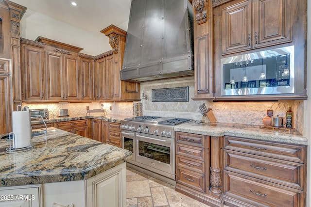 kitchen with light stone countertops, double oven range, backsplash, ventilation hood, and built in microwave