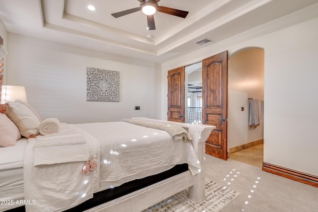 carpeted bedroom featuring ceiling fan and a raised ceiling