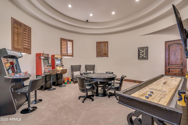 game room with a raised ceiling and light colored carpet