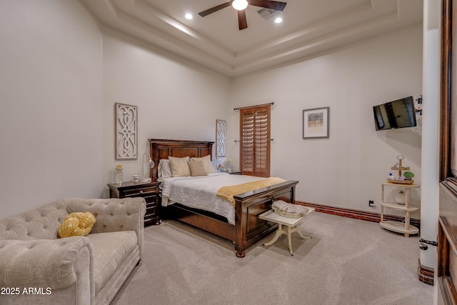 bedroom featuring ceiling fan, light colored carpet, a raised ceiling, and a towering ceiling