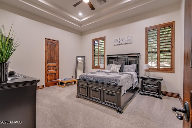 bedroom with light carpet, ceiling fan, and a tray ceiling