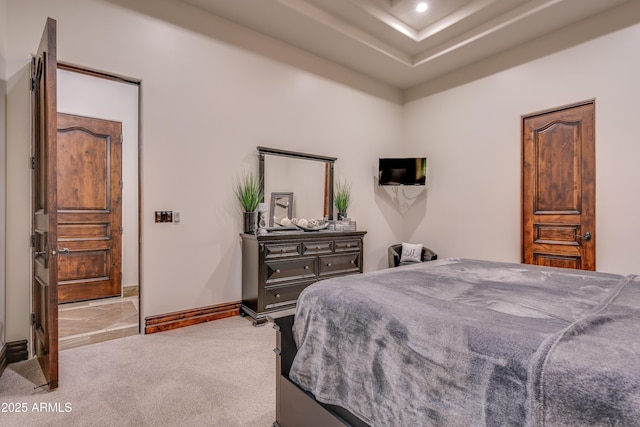 bedroom featuring light colored carpet and a raised ceiling