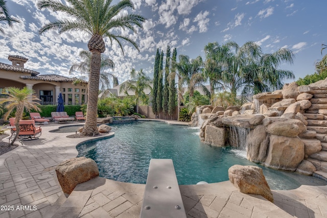 view of swimming pool with a patio area, a diving board, and pool water feature