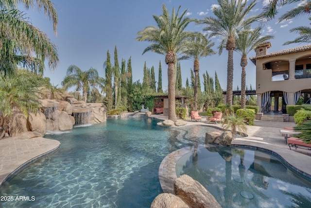 view of swimming pool with pool water feature and a patio