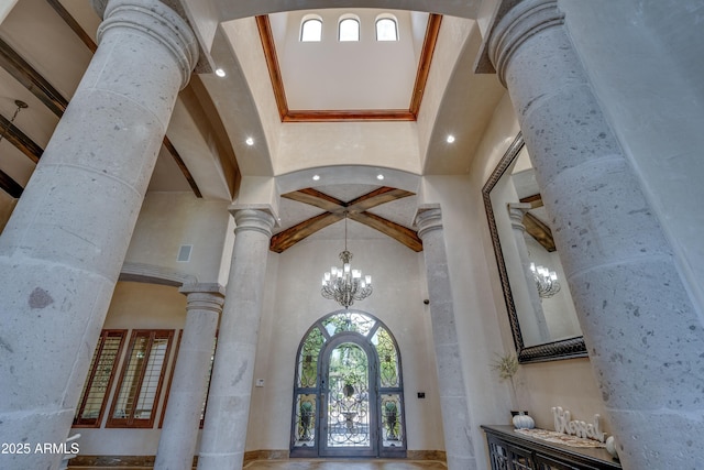 foyer featuring a high ceiling, an inviting chandelier, and decorative columns