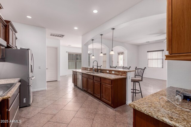 14552 S 182nd Dr, Goodyear, AZ 85338 - kitchen featuring visible vents, a breakfast bar, arched walkways, a sink, and stainless steel appliances