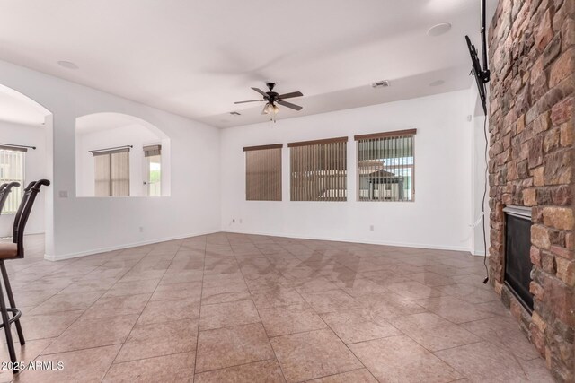 14552 S 182nd Dr, Goodyear, AZ 85338 - unfurnished living room featuring a stone fireplace, ceiling fan, a healthy amount of sunlight, and visible vents