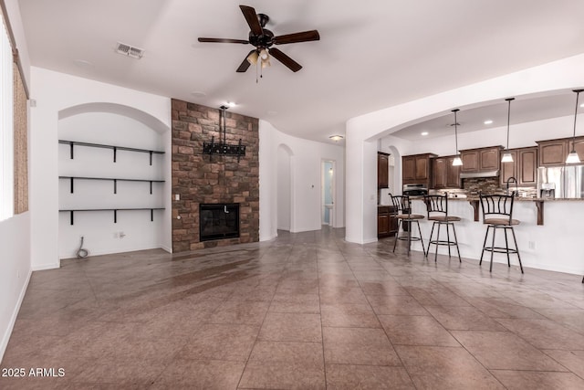 14552 S 182nd Dr, Goodyear, AZ 85338 - tiled living area with ceiling fan, arched walkways, a stone fireplace, baseboards, and visible vents