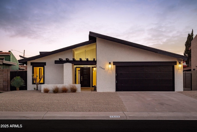 view of front of home with a garage, fence, driveway, and stucco siding