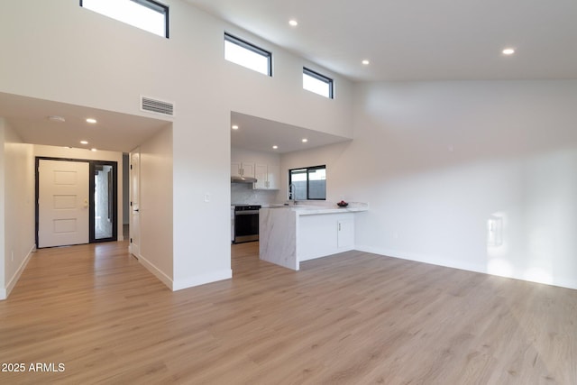 unfurnished living room with light wood-style flooring, plenty of natural light, and visible vents