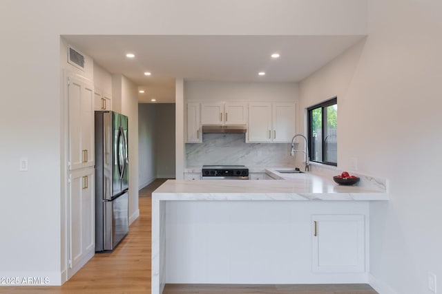 kitchen featuring visible vents, a sink, stainless steel fridge, range, and under cabinet range hood