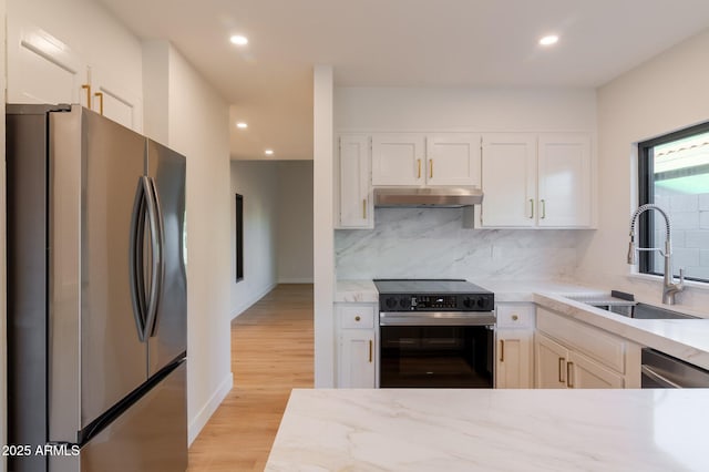 kitchen with stainless steel appliances, tasteful backsplash, white cabinets, a sink, and under cabinet range hood