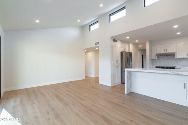 kitchen with light wood finished floors, freestanding refrigerator, and white cabinets