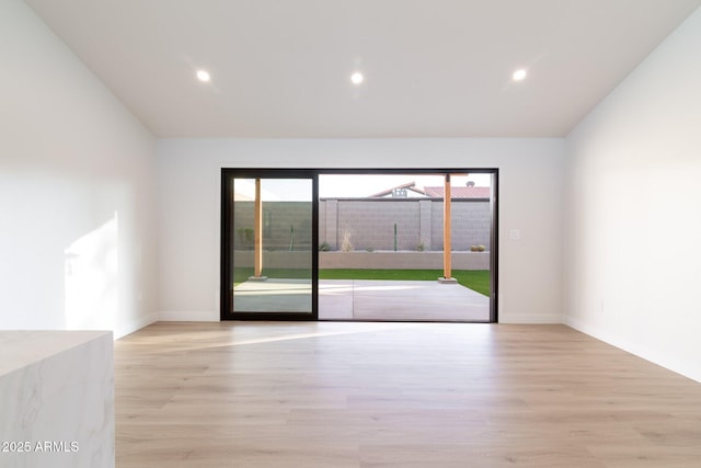 unfurnished room with vaulted ceiling, recessed lighting, light wood-style flooring, and baseboards