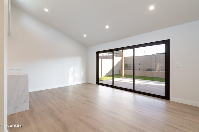 spare room featuring light wood-type flooring, lofted ceiling, baseboards, and recessed lighting