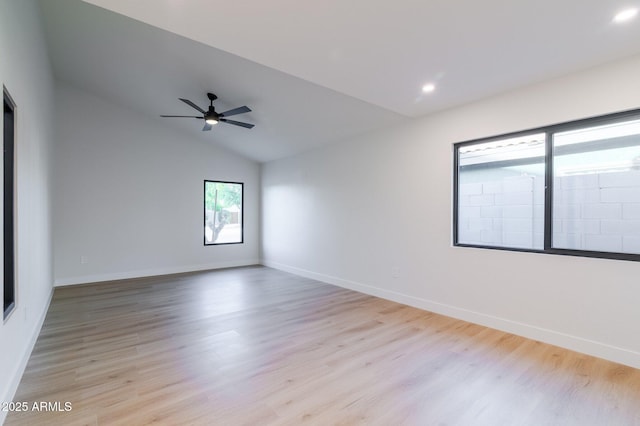 spare room featuring light wood-style flooring, baseboards, and vaulted ceiling