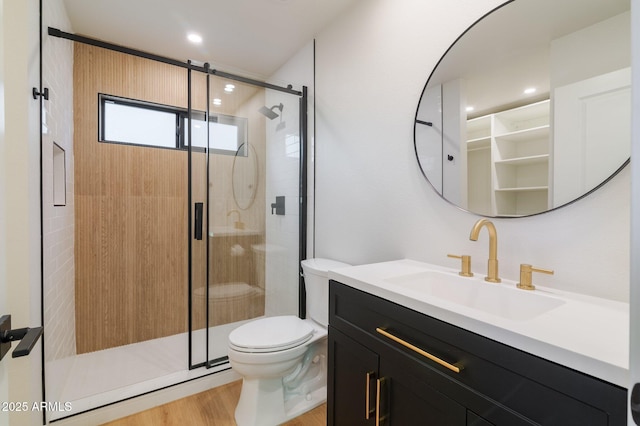 full bathroom featuring a stall shower, toilet, wood finished floors, vanity, and recessed lighting