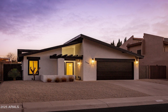 view of front of property with a garage, concrete driveway, fence, and stucco siding