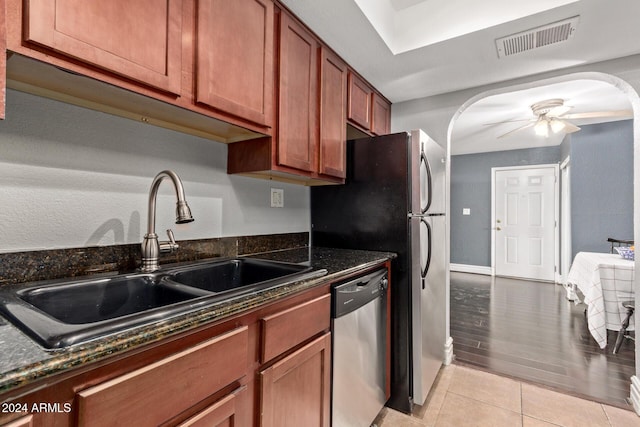 kitchen with ceiling fan, sink, stainless steel dishwasher, dark stone counters, and light hardwood / wood-style floors