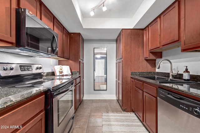 kitchen featuring sink, stainless steel appliances, dark stone countertops, track lighting, and light tile patterned floors